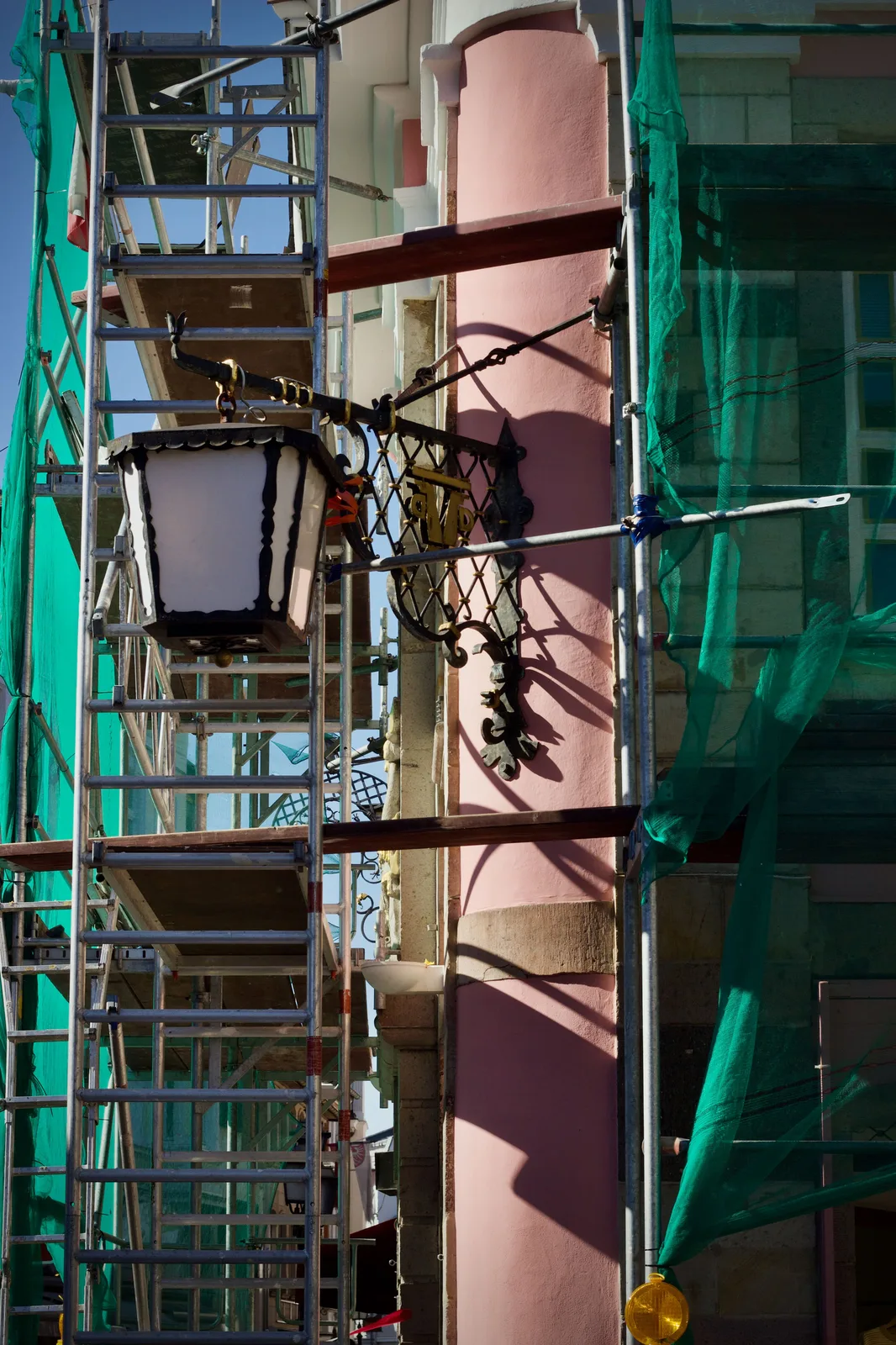 Edificio en rehabilitación de fachada con andamio y malla verde de protección (Plan Rehabilita Madrid 2026)
